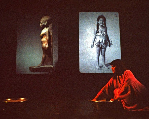 Told to swing an incense censer, she stirs sand instead, performance Nefertiti/Devonia Evangeline by Lorraine O’Grady.