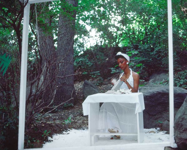 The Woman in White continues grating coconut, performance Rivers First Draft by Lorraine O’Grady.